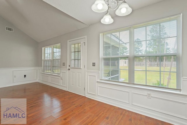 138 Forest St NE, Ludowici, GA 31316 - unfurnished dining area featuring a chandelier, wood finished floors, vaulted ceiling, a wainscoted wall, and a decorative wall
