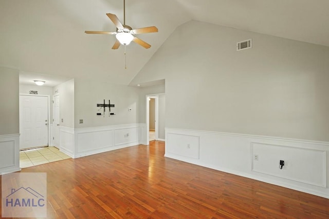 138 Forest St NE, Ludowici, GA 31316 - unfurnished living room featuring a ceiling fan, wainscoting, wood finished floors, high vaulted ceiling, and a decorative wall