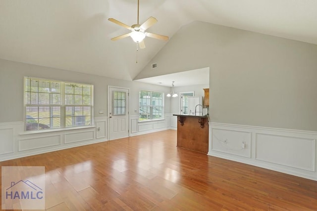 138 Forest St NE, Ludowici, GA 31316 - unfurnished living room featuring wood finished floors, a ceiling fan, a wainscoted wall, a decorative wall, and a chandelier