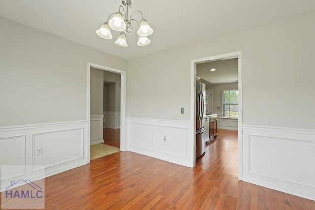 138 Forest St NE, Ludowici, GA 31316 - unfurnished room with a chandelier, wainscoting, wood finished floors, and a decorative wall
