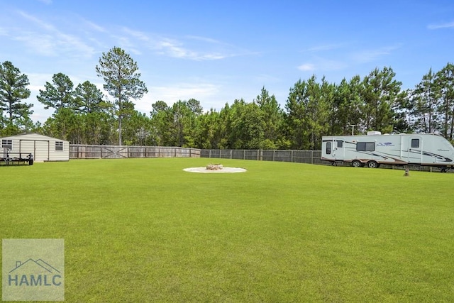 138 Forest St NE, Ludowici, GA 31316 - fenced backyard with a storage unit, a fire pit, and view of wooded area