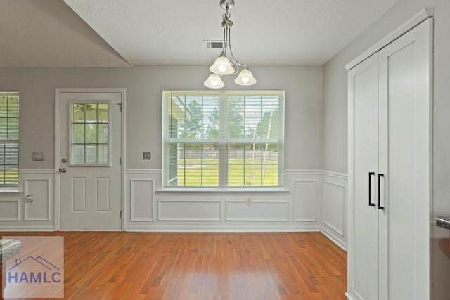138 Forest St NE, Ludowici, GA 31316 - unfurnished dining area featuring wainscoting, light wood-style flooring, and a decorative wall