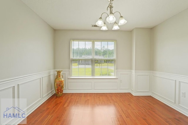 138 Forest St NE, Ludowici, GA 31316 - empty room featuring a chandelier, wood finished floors, a wainscoted wall, and a decorative wall