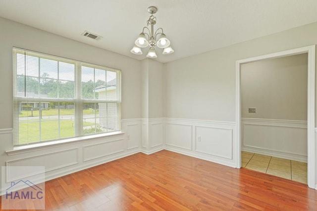 138 Forest St NE, Ludowici, GA 31316 - empty room featuring a chandelier, light wood finished floors, wainscoting, and a decorative wall