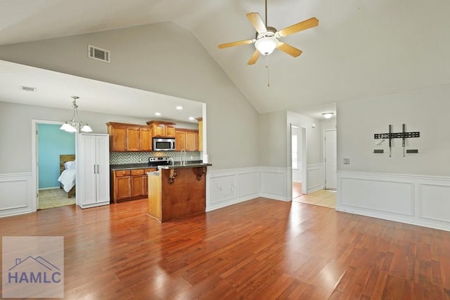138 Forest St NE, Ludowici, GA 31316 - kitchen featuring stainless steel appliances, brown cabinetry, dark countertops, open floor plan, and wainscoting