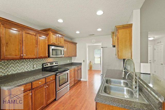 138 Forest St NE, Ludowici, GA 31316 - kitchen featuring appliances with stainless steel finishes, light wood-style flooring, dark countertops, brown cabinetry, and recessed lighting