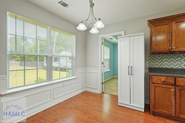 138 Forest St NE, Ludowici, GA 31316 - unfurnished dining area with a chandelier, light wood finished floors, and wainscoting