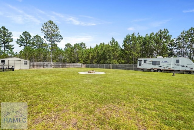 138 Forest St NE, Ludowici, GA 31316 - fenced backyard with an outdoor fire pit, a shed, and view of scattered trees