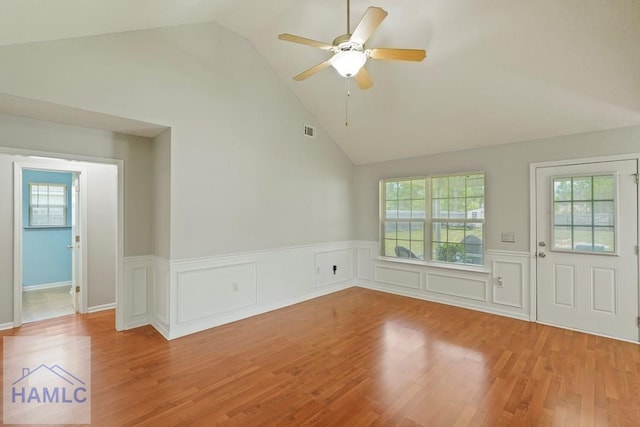 138 Forest St NE, Ludowici, GA 31316 - empty room with a wainscoted wall, lofted ceiling, wood finished floors, a ceiling fan, and healthy amount of natural light