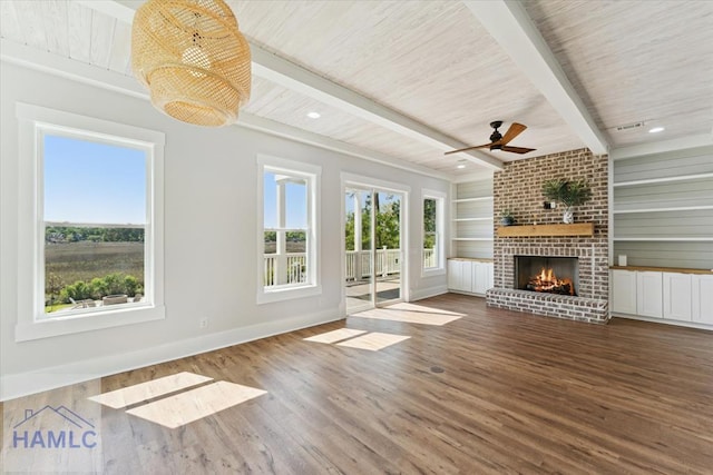 1018 Sweet Hill Rd, Richmond Hill, GA 31324 - unfurnished living room featuring wood finished floors, baseboards, a fireplace, beamed ceiling, and ceiling fan