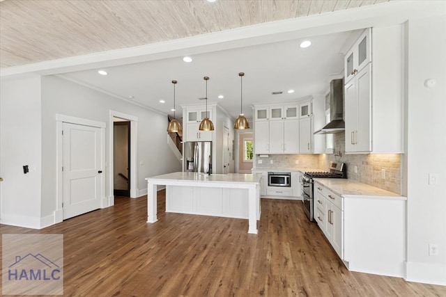 kitchen featuring a breakfast bar, stainless steel appliances, backsplash, baseboards, and wall chimney exhaust hood