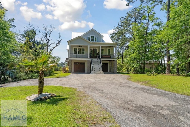 coastal inspired home featuring driveway, an attached garage, stairway, a porch, and a front lawn
