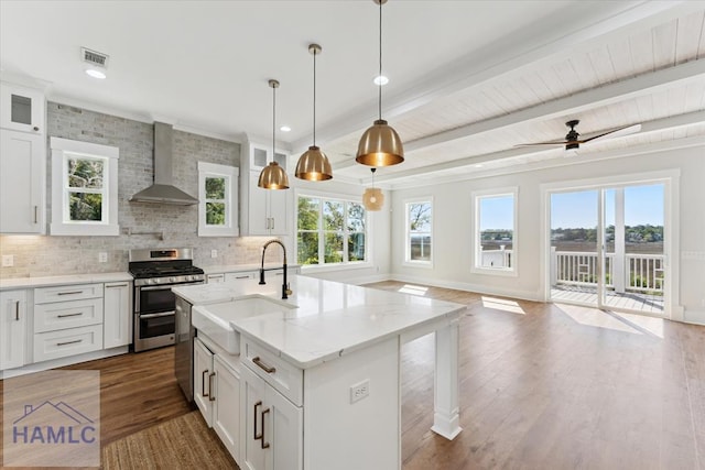 kitchen featuring a sink, stainless steel appliances, dark wood-type flooring, visible vents, and wall chimney range hood