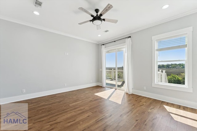 spare room with ceiling fan, visible vents, baseboards, ornamental molding, and wood finished floors