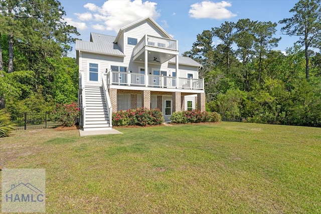 exterior space with stairway, ceiling fan, brick siding, a balcony, and a lawn