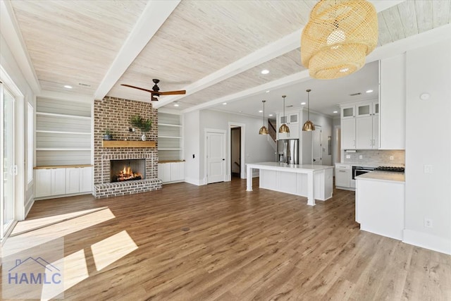 unfurnished living room featuring a fireplace, ceiling fan, light wood-style flooring, and wooden ceiling