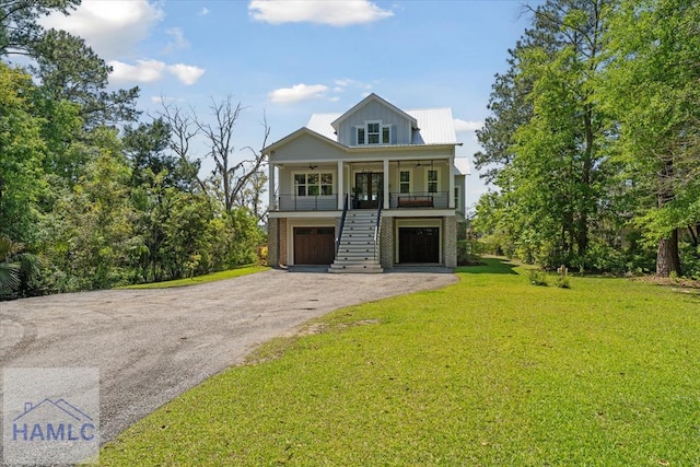 coastal home with a porch, a front lawn, stairway, a garage, and ceiling fan