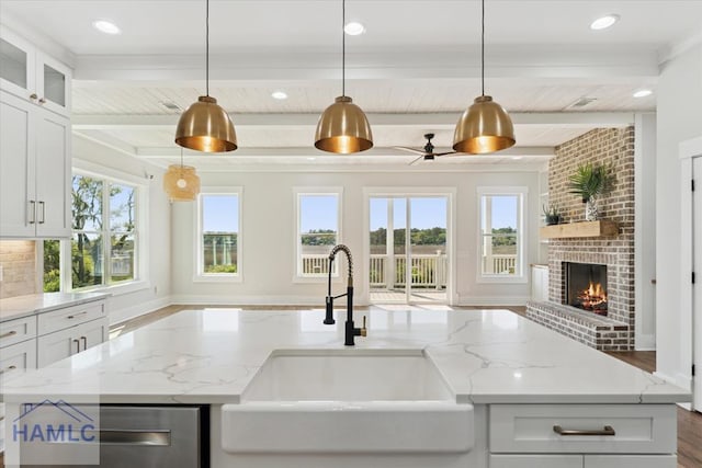 kitchen featuring a fireplace, a sink, beam ceiling, and a healthy amount of sunlight
