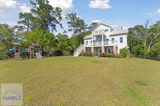 exterior space featuring a front lawn, stairway, a balcony, a playground, and fence