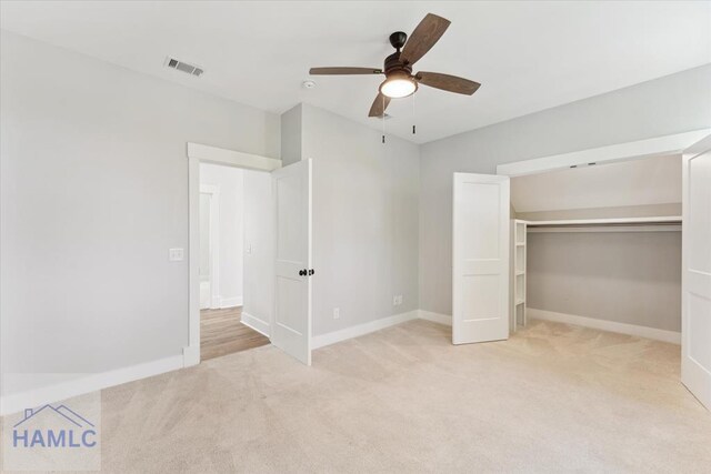 unfurnished bedroom featuring ceiling fan, visible vents, a closet, baseboards, and light carpet