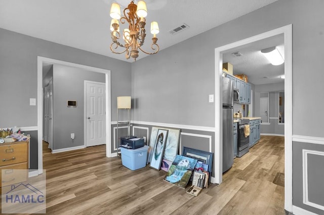 dining space featuring hardwood / wood-style floors, a textured ceiling, and an inviting chandelier