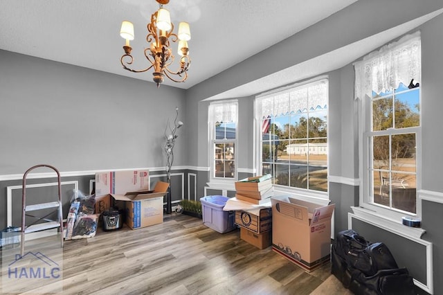 interior space with a wealth of natural light, wood-type flooring, and a notable chandelier