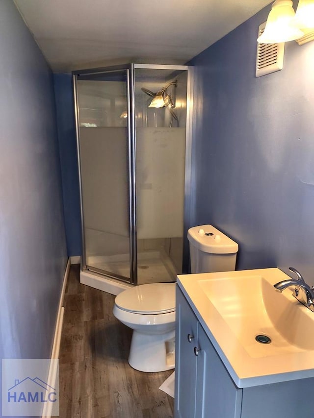 bathroom with hardwood / wood-style flooring, vanity, toilet, and a shower with door