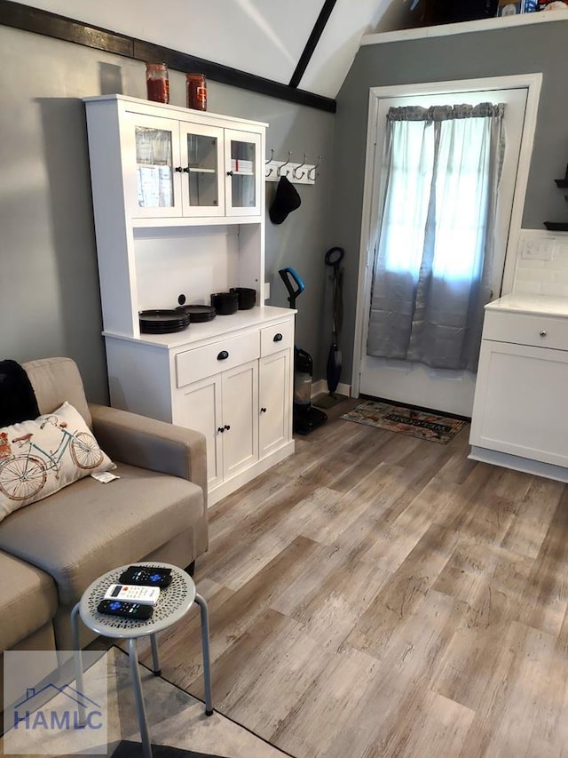 living area featuring lofted ceiling and light hardwood / wood-style flooring