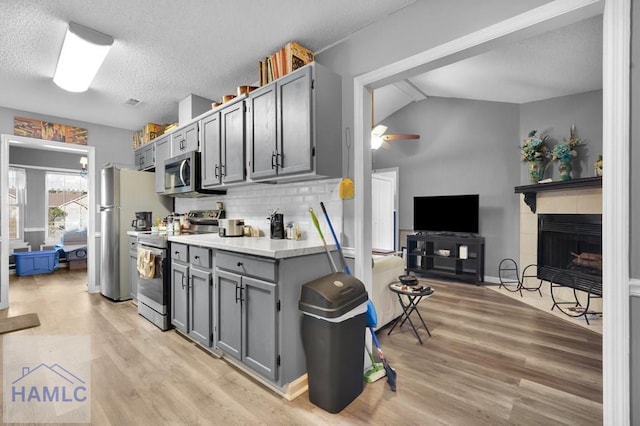 kitchen featuring ceiling fan, light wood-type flooring, vaulted ceiling, and appliances with stainless steel finishes