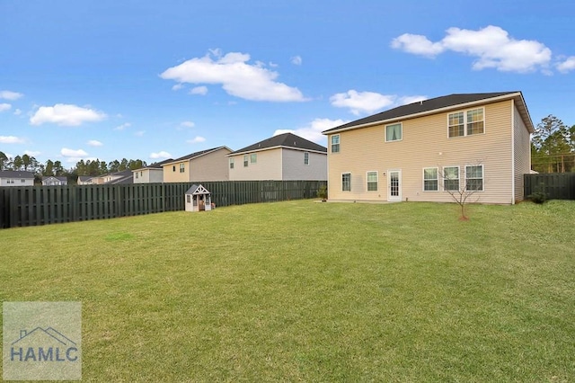 rear view of house featuring a yard, a fenced backyard, and a residential view