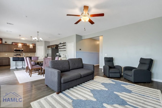 living room with visible vents, dark wood-style flooring, and ceiling fan with notable chandelier