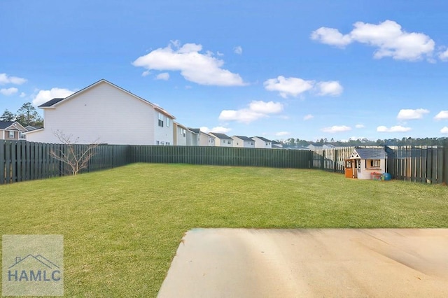 view of yard with a fenced backyard, an outdoor structure, a storage unit, and a residential view