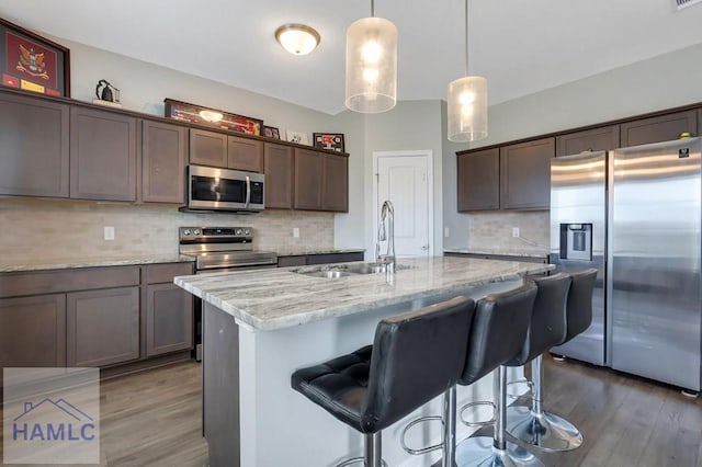 kitchen with backsplash, light wood finished floors, stainless steel appliances, and a sink