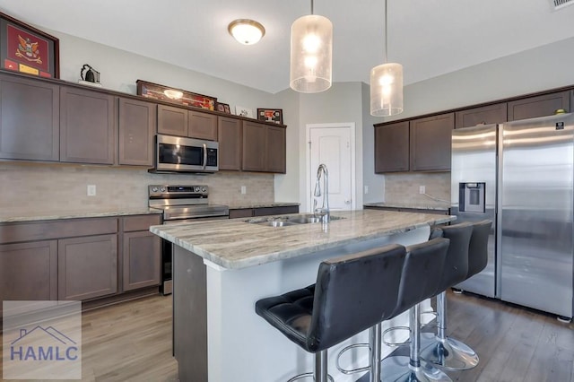 kitchen with tasteful backsplash, light wood-style flooring, appliances with stainless steel finishes, and a sink