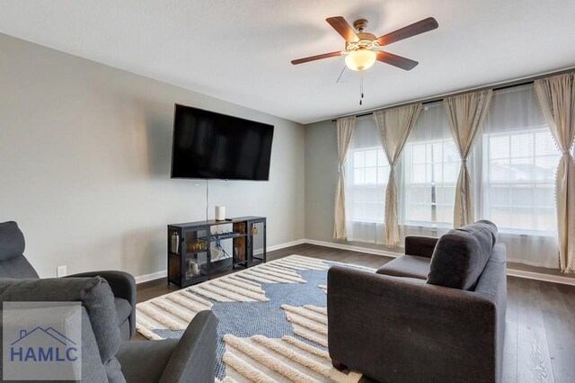 living area with dark wood-type flooring, a ceiling fan, and baseboards