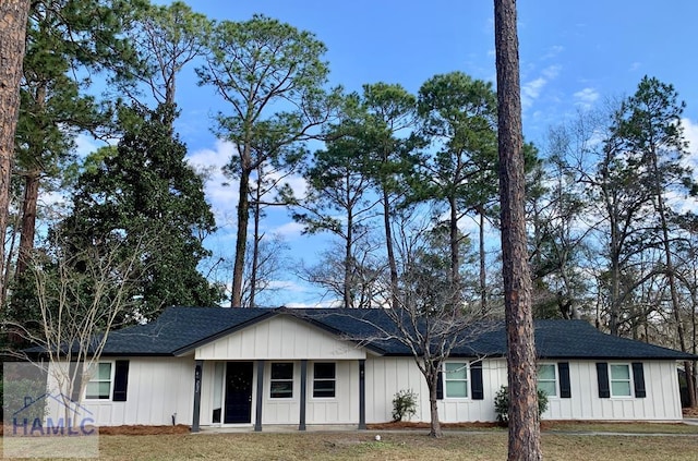 single story home with board and batten siding, roof with shingles, and a front lawn