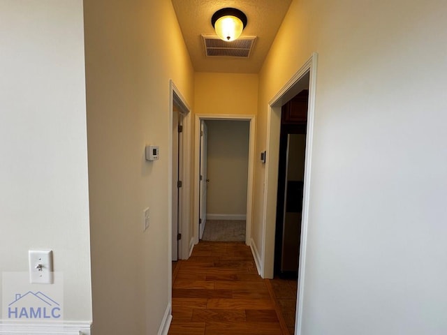 hall with baseboards, wood finished floors, and visible vents