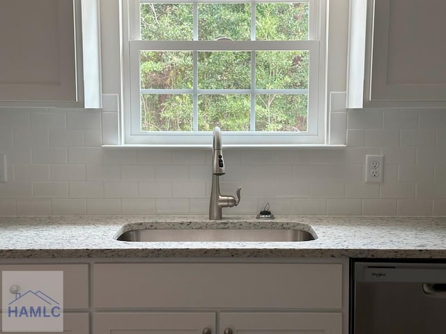 room details featuring white cabinets, light stone counters, tasteful backsplash, sink, and dishwasher