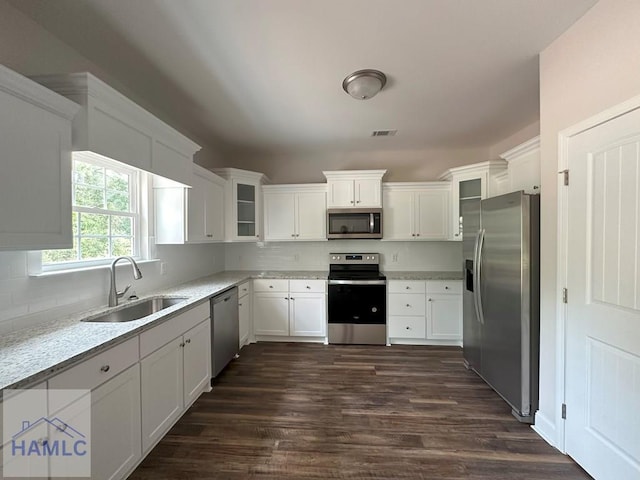 kitchen with light stone counters, stainless steel appliances, sink, dark hardwood / wood-style floors, and white cabinetry