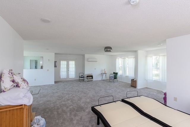 bedroom featuring light colored carpet, a textured ceiling, a wall unit AC, and multiple windows