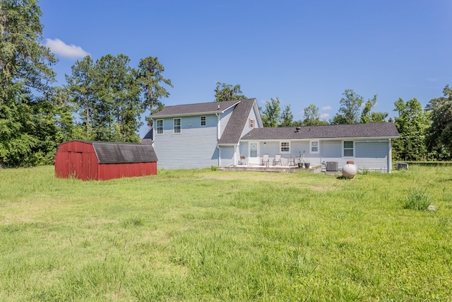 rear view of property with central AC, a yard, and a shed