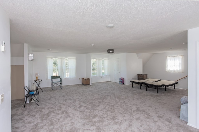 living area featuring a wealth of natural light, light colored carpet, and a textured ceiling