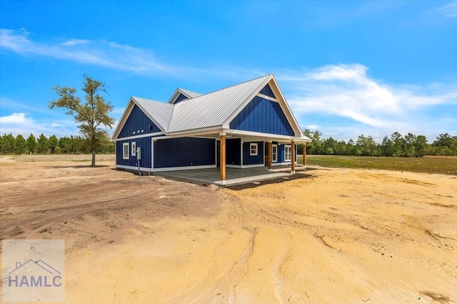 view of side of property featuring covered porch, metal roof, and board and batten siding