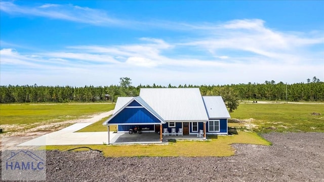 back of house featuring a yard, an attached carport, a patio area, and metal roof