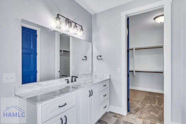 bathroom with a walk in closet, vanity, and baseboards