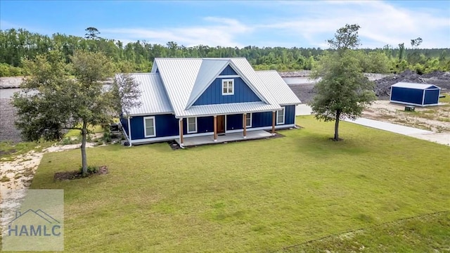 back of property featuring covered porch, a lawn, metal roof, and board and batten siding