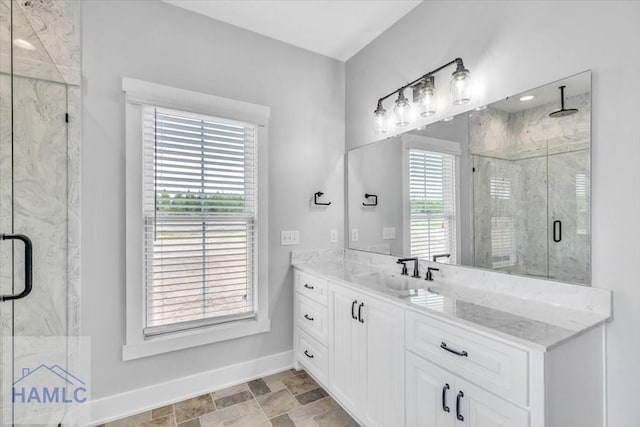 full bathroom featuring baseboards, a marble finish shower, vanity, and stone finish flooring