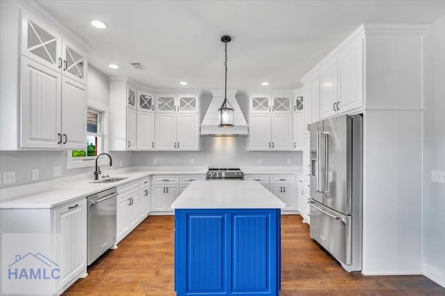 kitchen with appliances with stainless steel finishes, a sink, custom range hood, a center island, and white cabinets