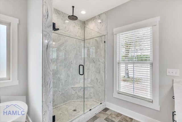 bathroom with a marble finish shower, baseboards, and stone finish floors