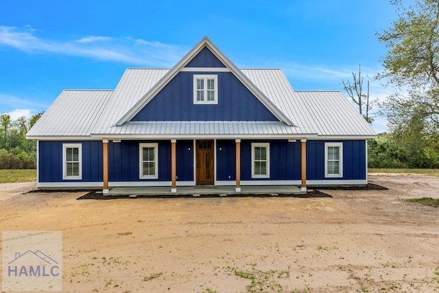 modern farmhouse with board and batten siding, a porch, and metal roof